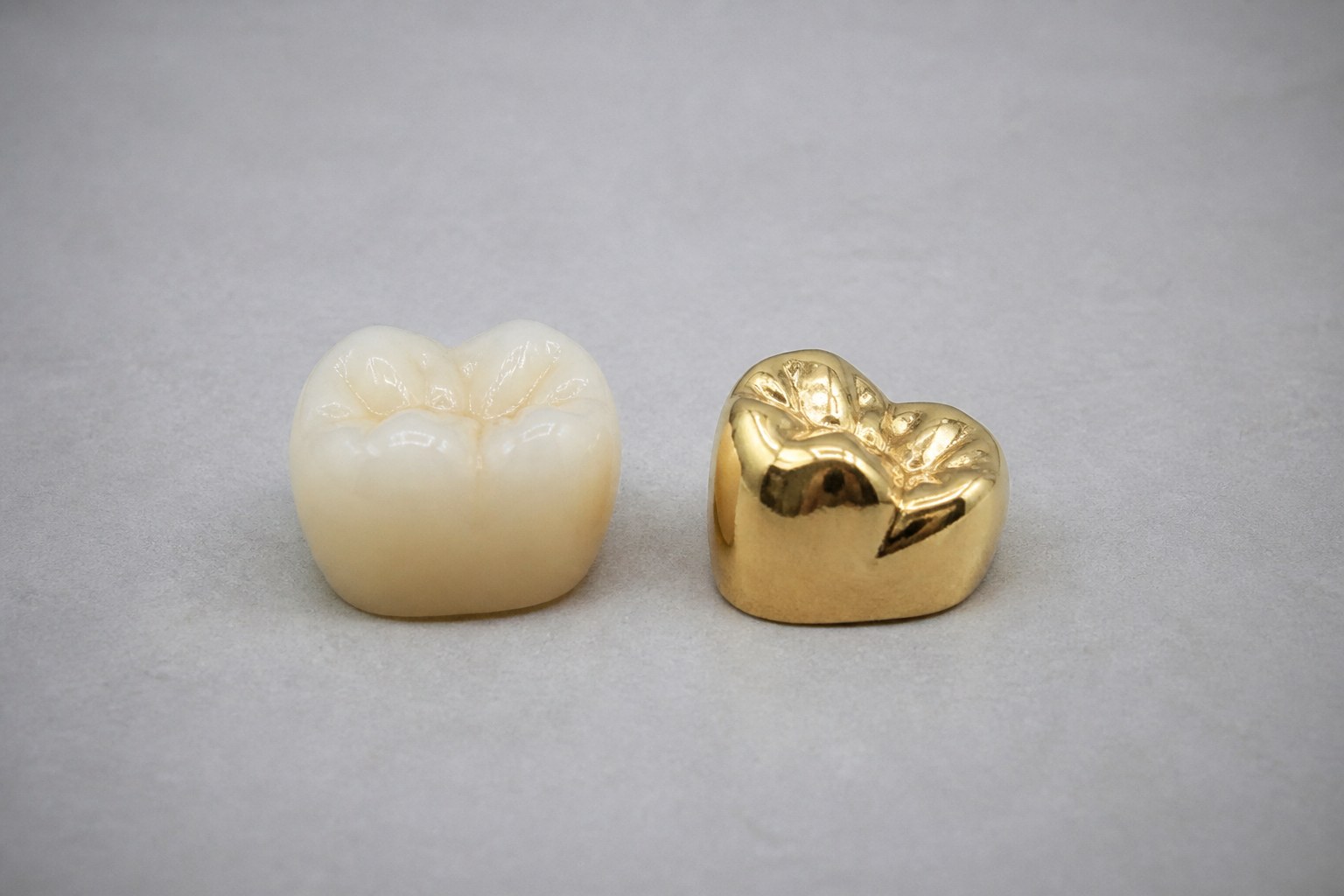Porcelain crown and gold crown compared side by side on a neutral surface